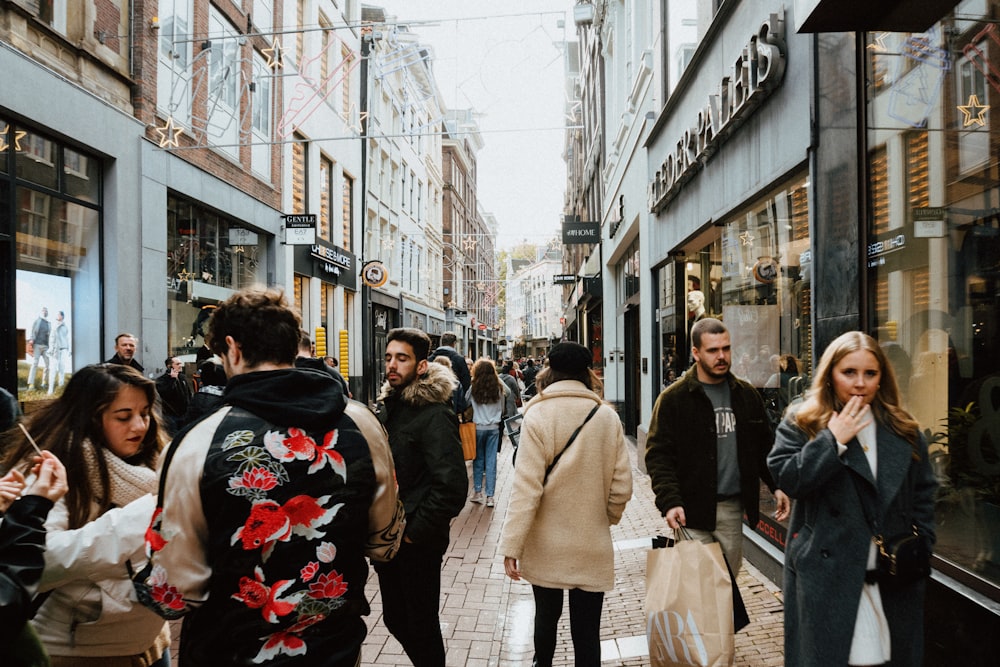 a group of people walking down a street next to tall buildings