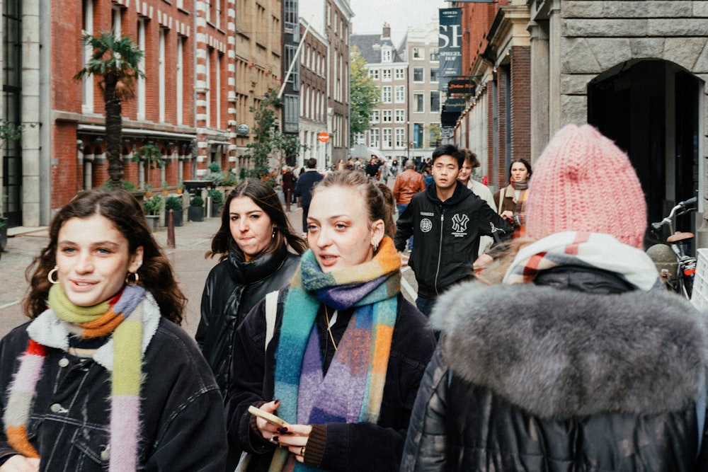 a group of people walking down a street next to tall buildings