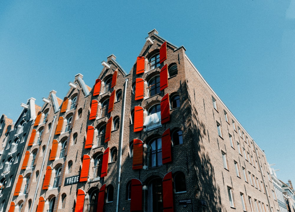 a tall brick building with red shutters on the windows