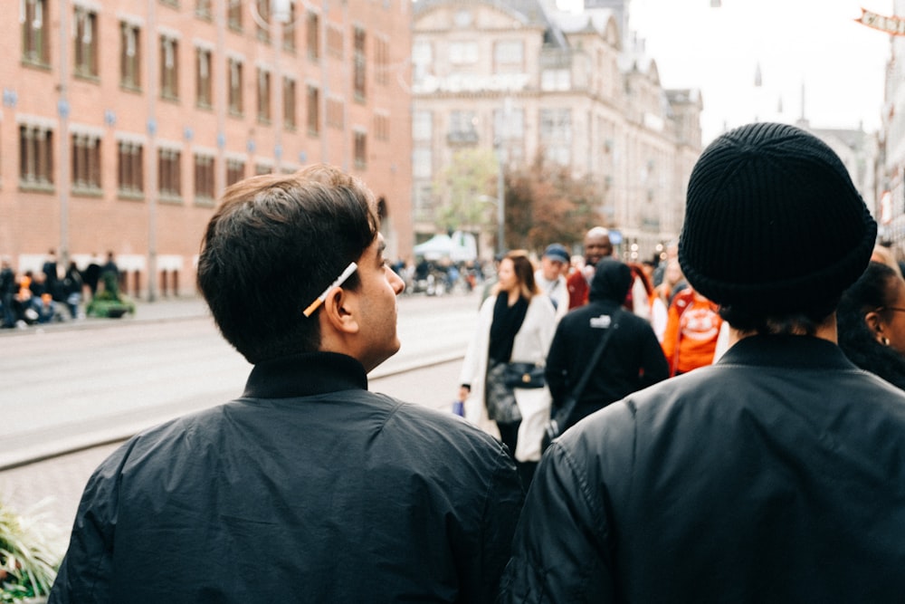 two men standing next to each other on a street