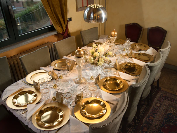 Elegant dining table set with gold accents and flickering candlelight in a dark navy and black interior