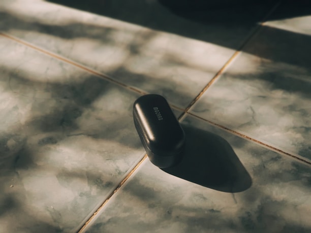 A sleek black phone case with reinforced corners lying on a wooden desk beside a charging cable.