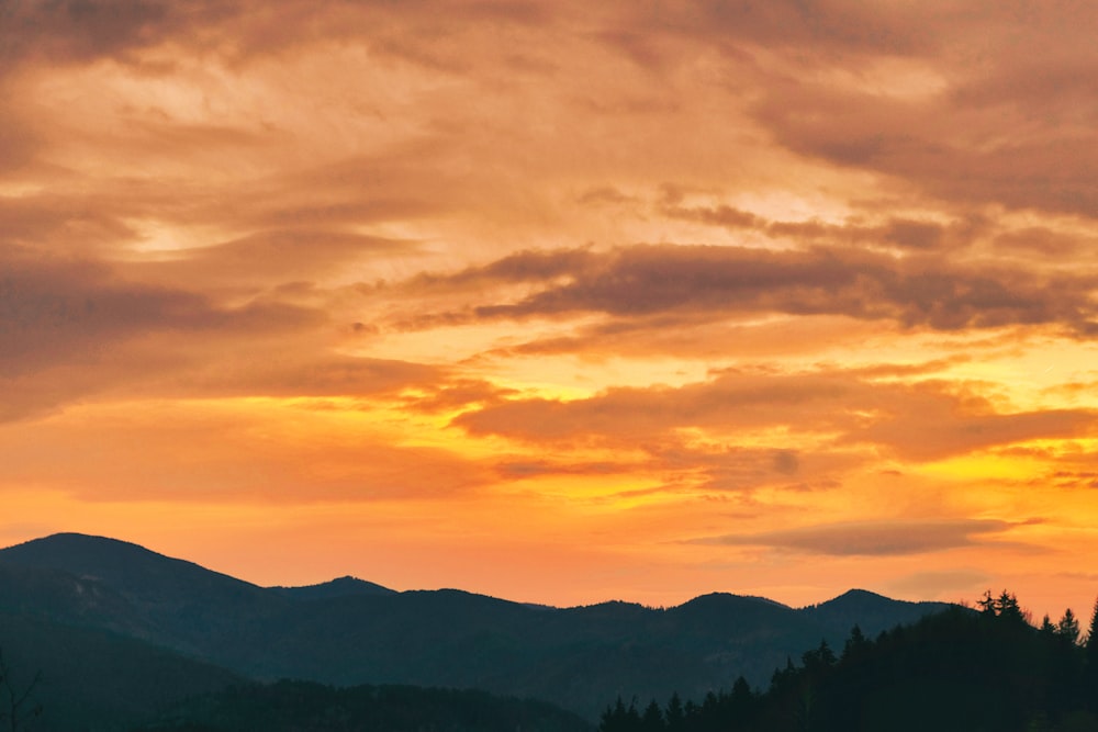 a plane flying over a mountain range at sunset