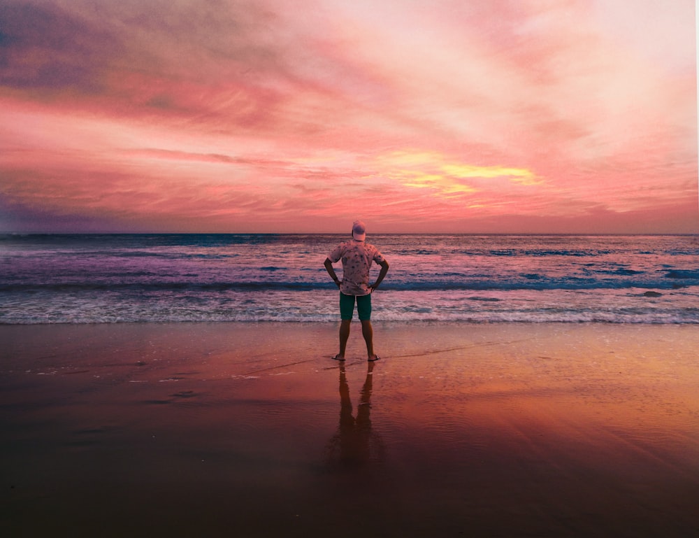 a man standing on top of a beach next to the ocean