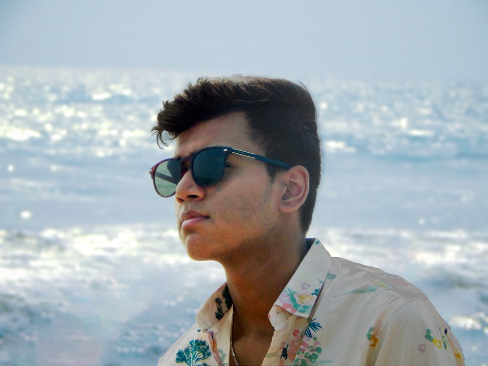 a man wearing sunglasses on a beach near the ocean