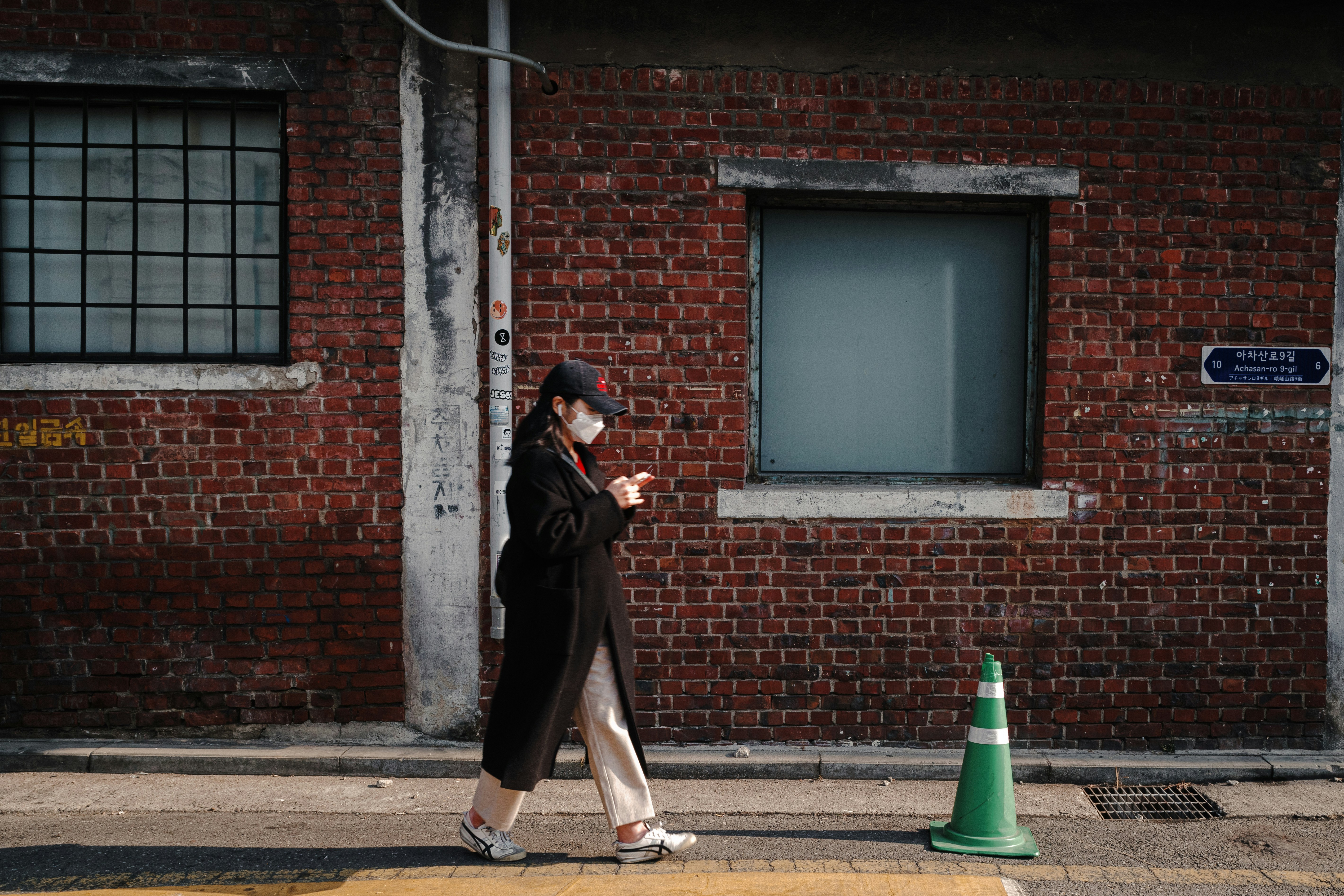a woman walking down a street past a brick building