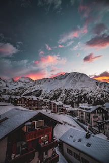 Snow-covered rooftops in Austria framed by majestic alpine mountains at dawn.