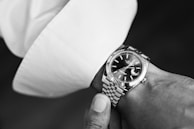 Artful black and white shot of refined lifestyle details: a wristwatch on a cuffed sleeve.