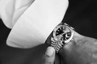 Artful black and white shot of refined lifestyle details: a wristwatch on a cuffed sleeve.