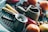 An assortment of cooking utensils and vegetables are placed on a grill. A small metal pot with a textured surface is prominently displayed in the foreground, surrounded by a wooden mortar and pestle. Various vegetables, including carrots and onions, add a splash of color to the scene.