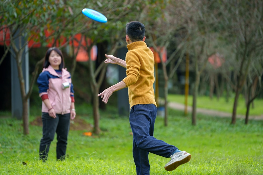 a man and a woman playing frisbee in a park