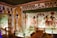 A richly decorated ancient Egyptian tomb with intricate hieroglyphs and colorful wall paintings featuring deities and symbolic figures. The room is illuminated by strategic lighting, showcasing the detail of the artwork and architectural features, including carved pillars and ornate borders.