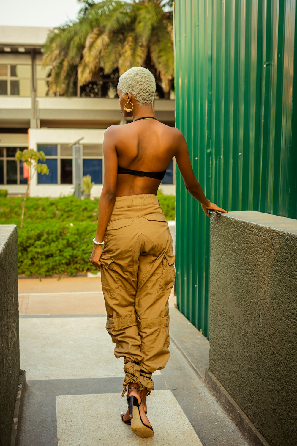 a woman walking down a sidewalk next to a green building