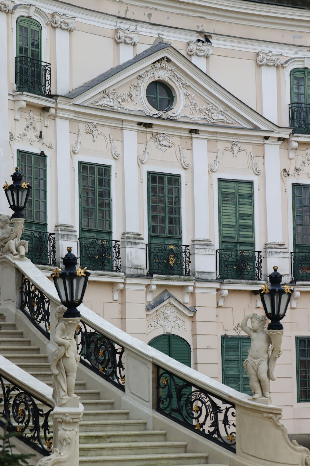 a white building with green shutters and a staircase