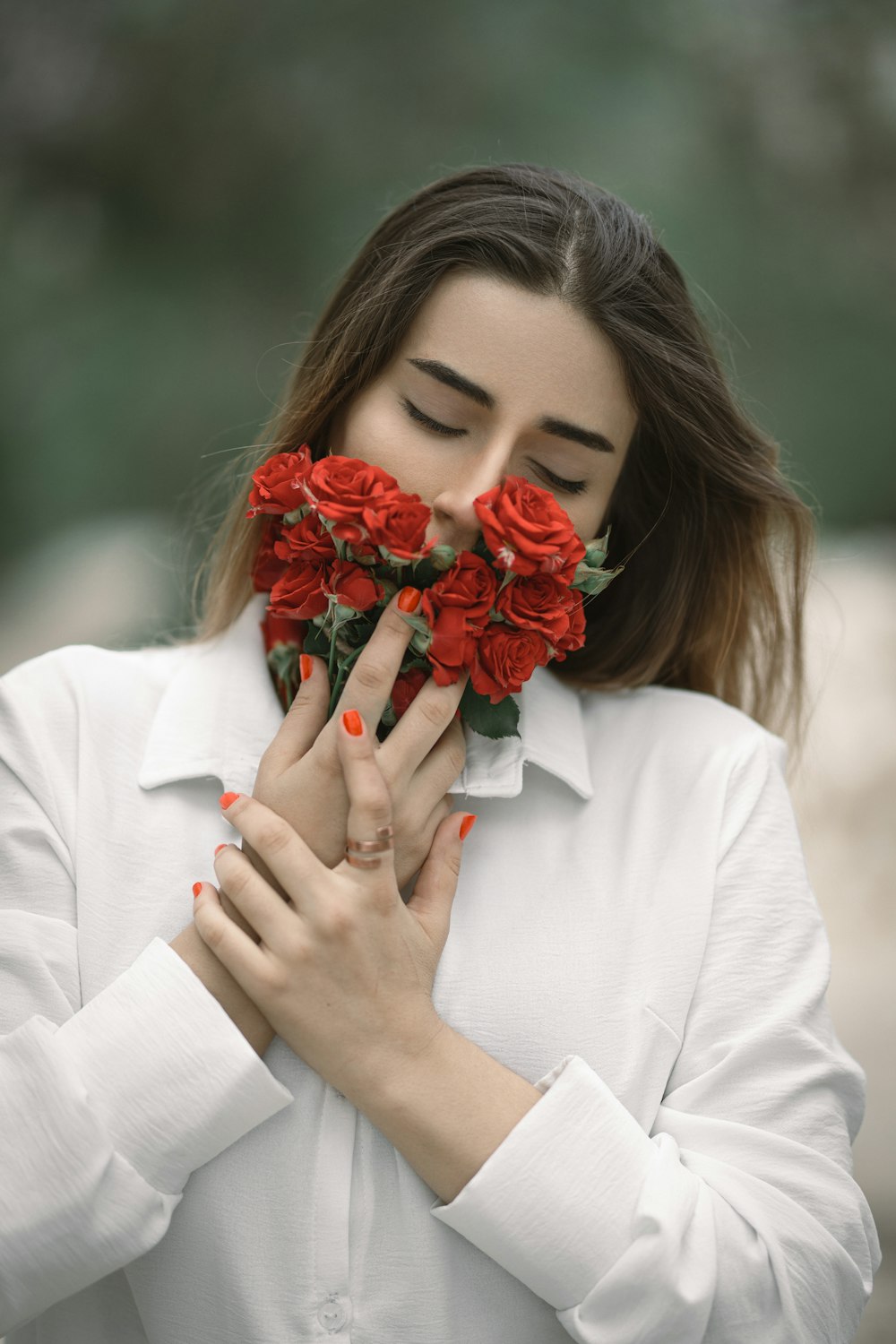 a woman holding a bunch of red roses in her hands