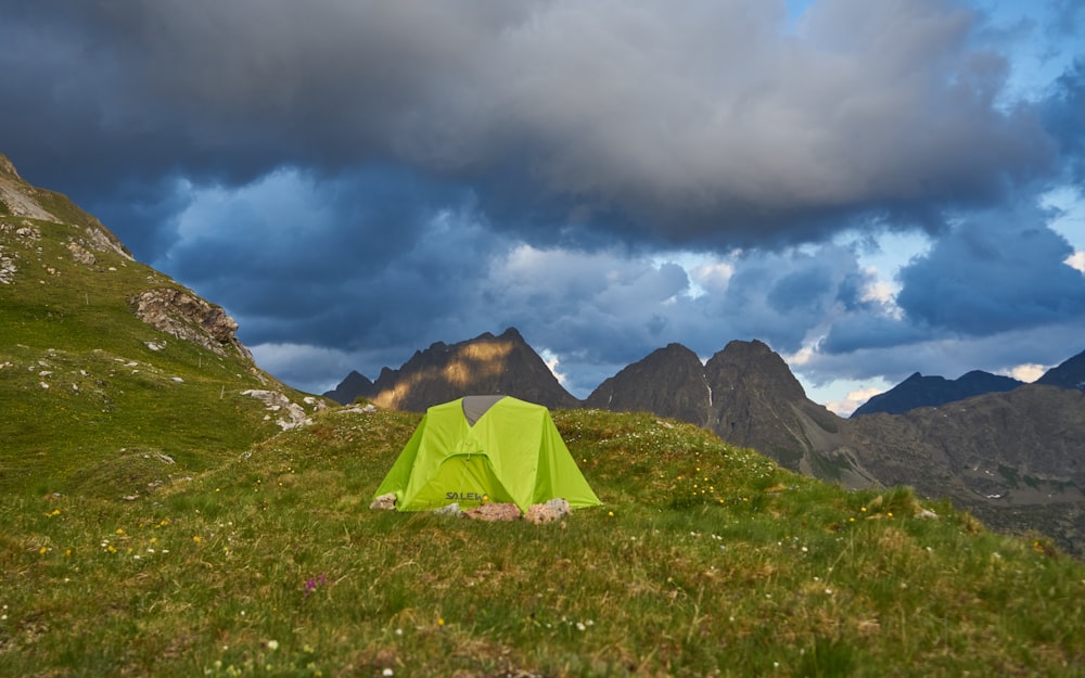 a green tent sitting on top of a lush green hillside