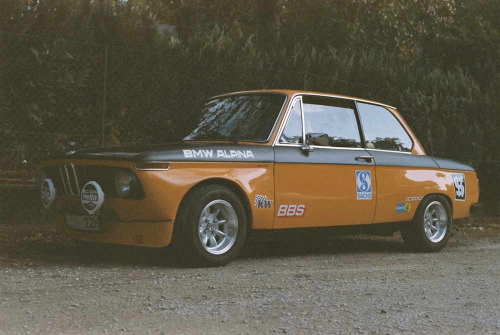 an orange and black car parked in front of a bush