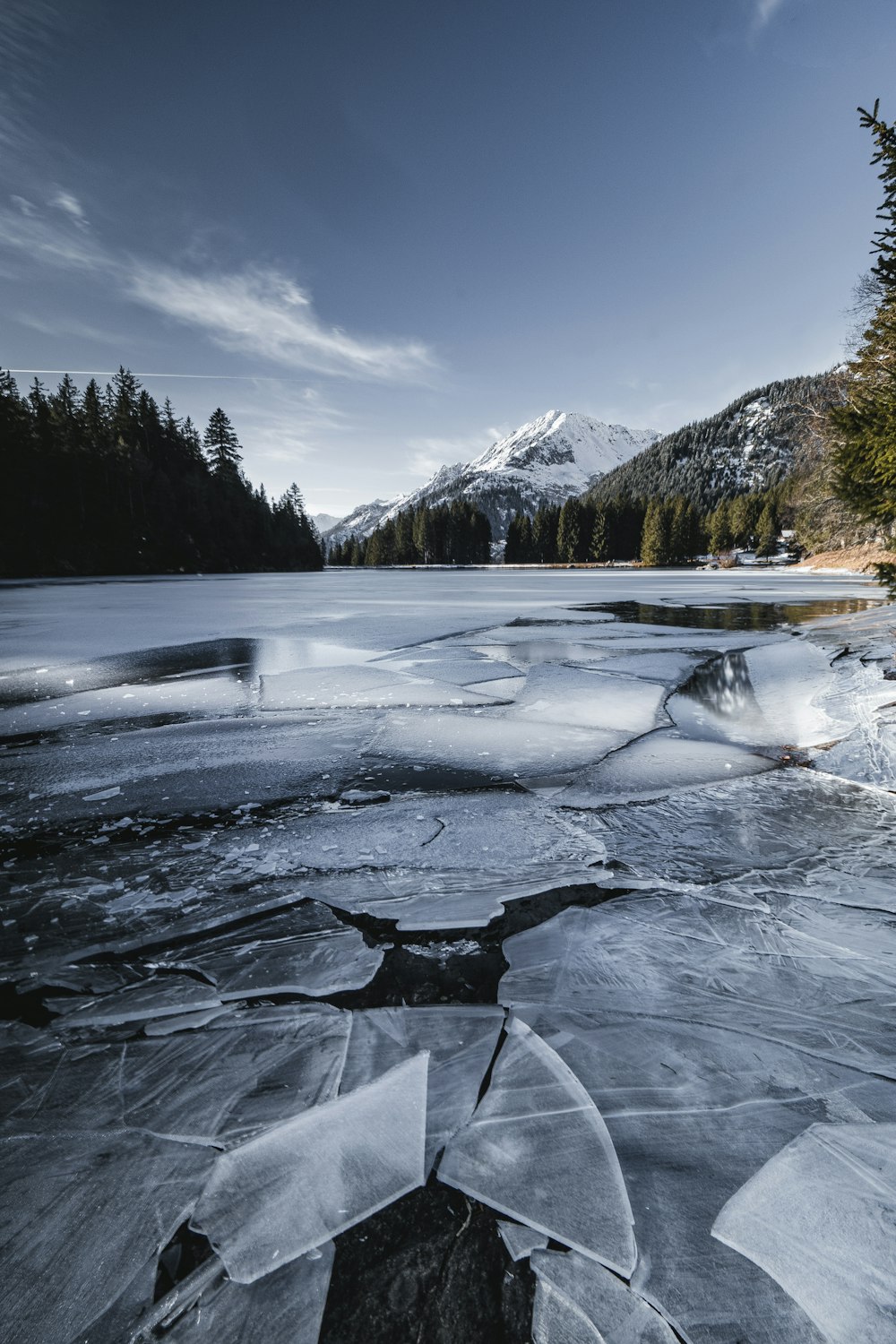 Un lago congelado con árboles y montañas al fondo