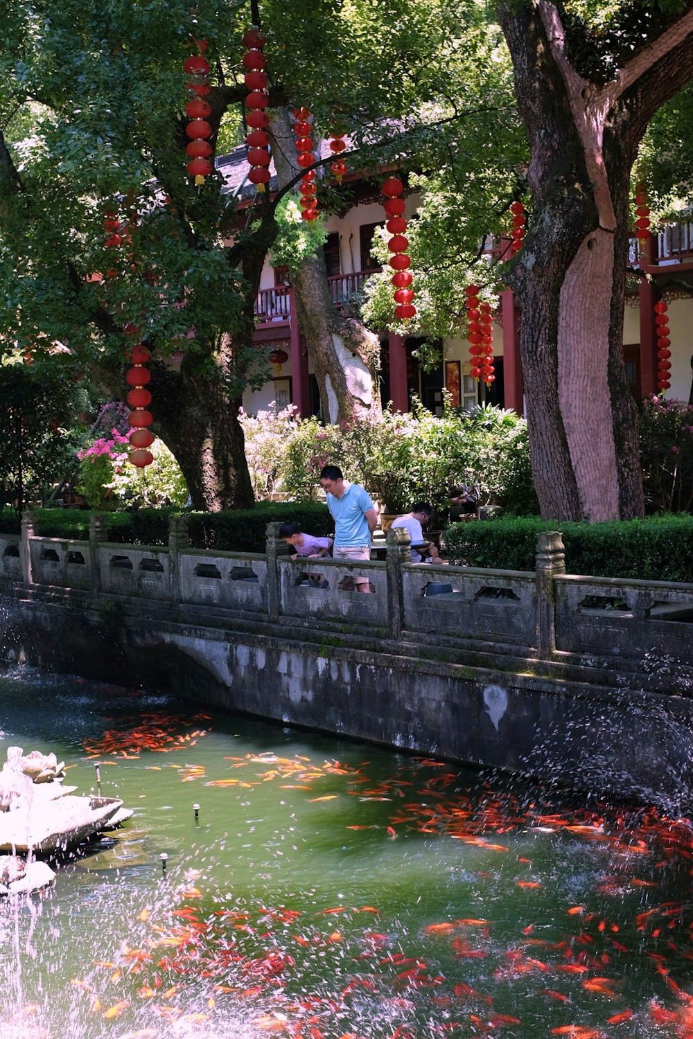 a group of people sitting on a bridge over a pond