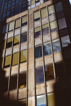 Wide shot of a building facade featuring large metal-framed windows reflecting the sky.