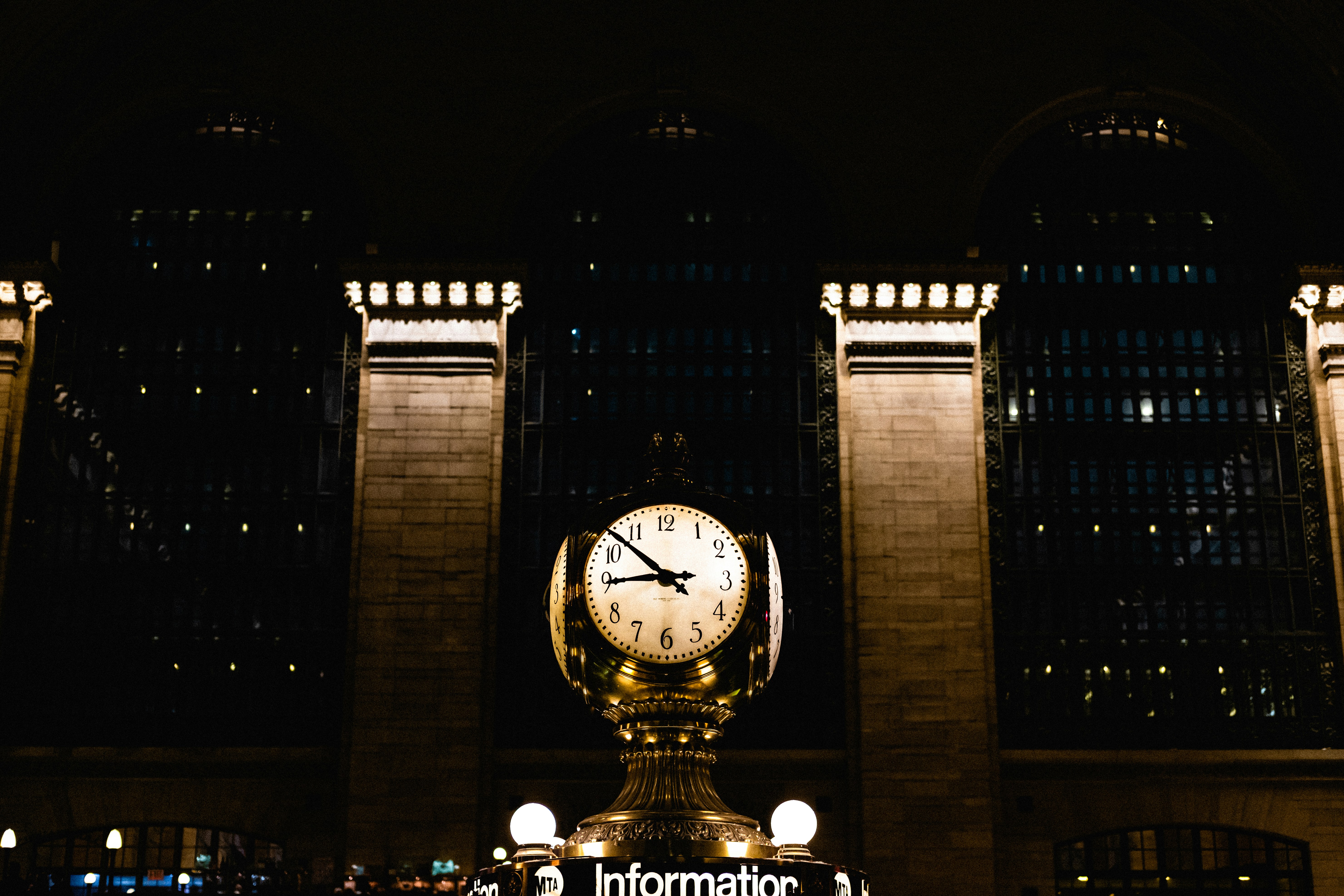 a large clock in front of a building at night