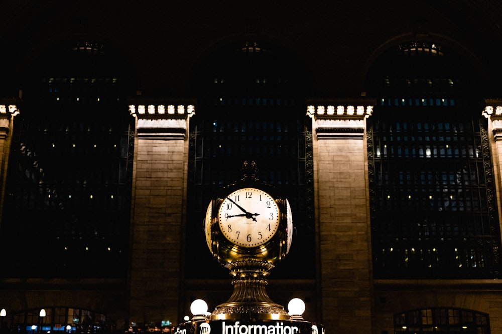 a large clock in front of a building at night