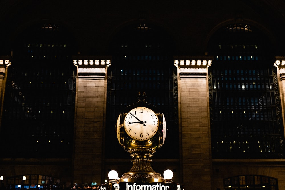 um grande relógio em frente a um edifício à noite