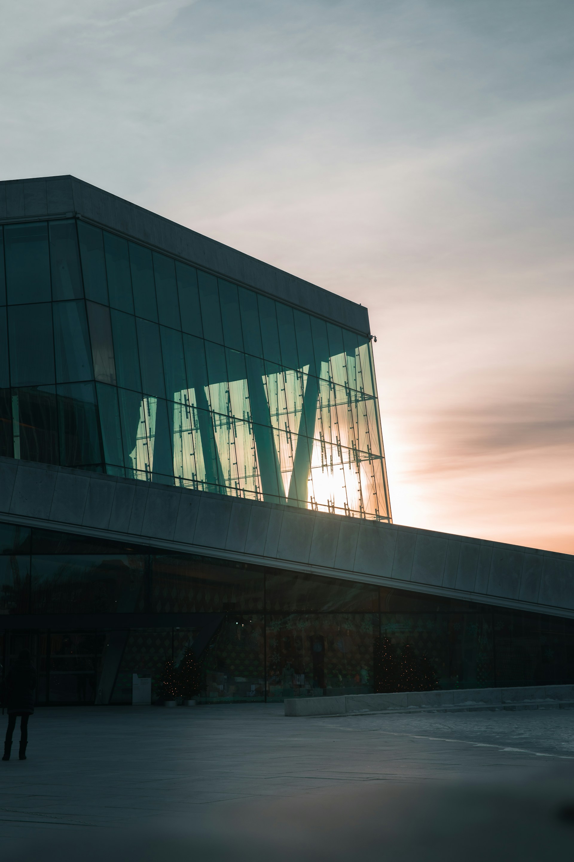 A sleek, modern apartment building with large glass windows reflecting the city skyline at sunset.