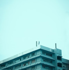 A large commercial building with a flat roof and workers inspecting it.