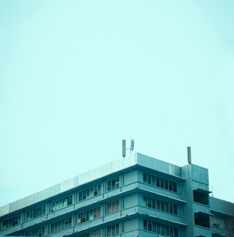 A large commercial building with a flat roof and workers inspecting it.