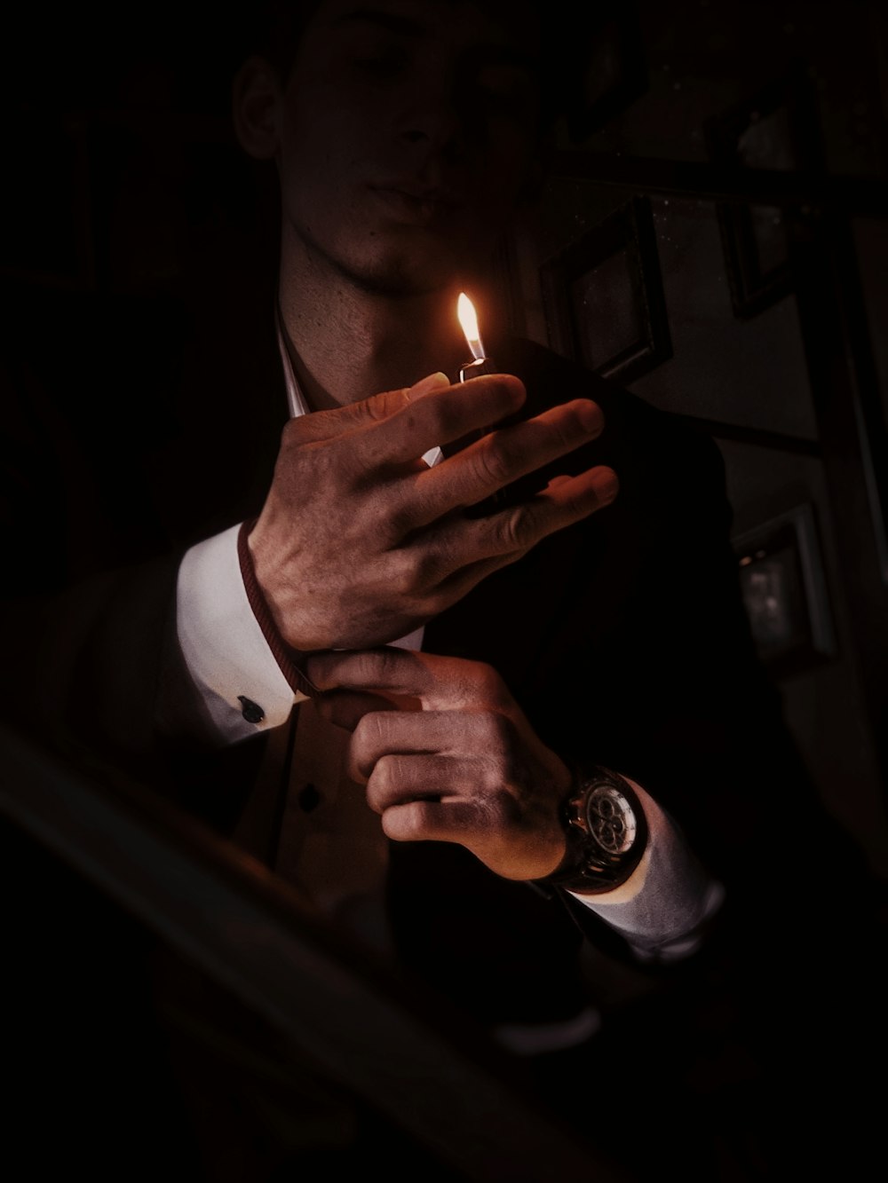 a man in a suit holding a lit candle in his hand