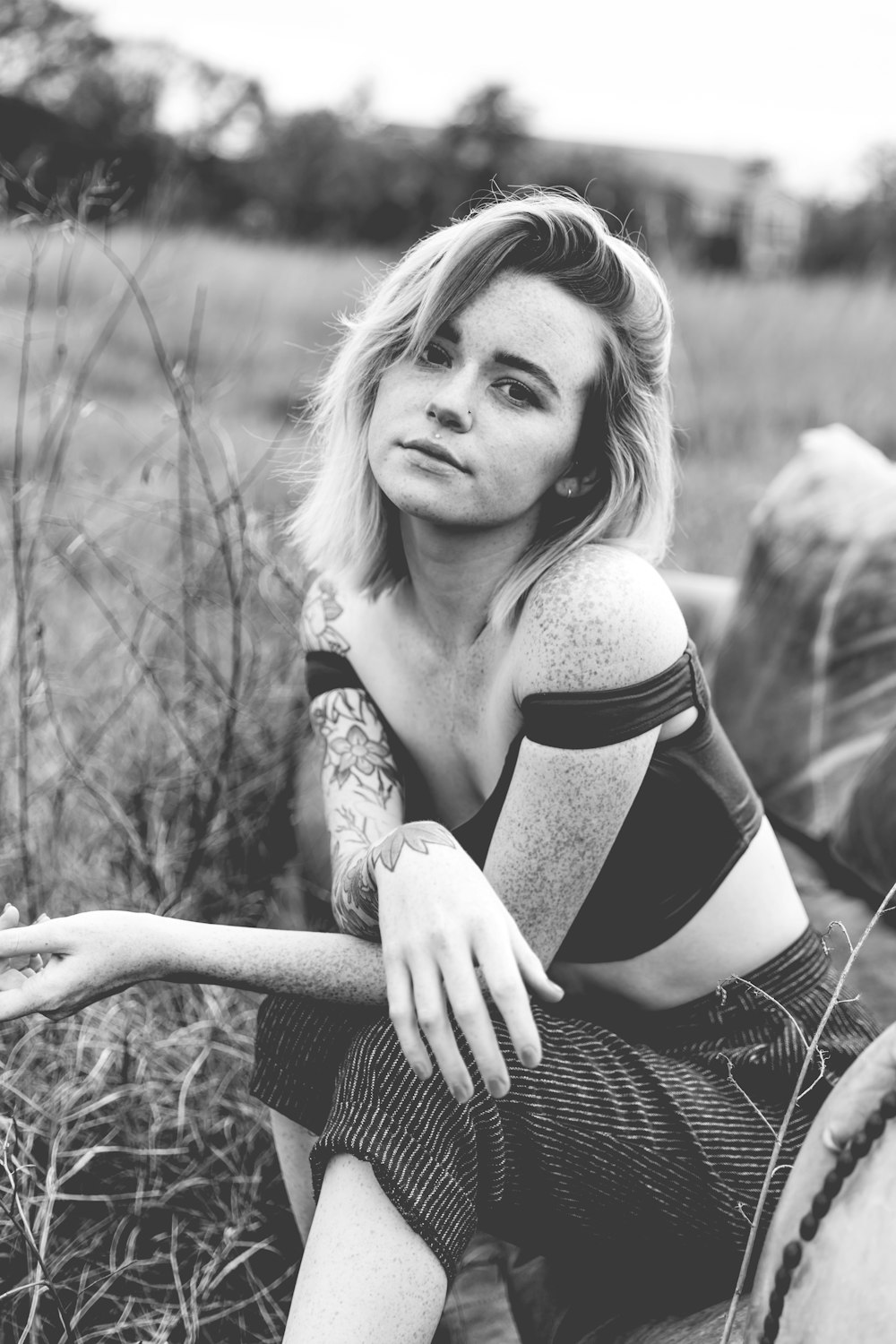 a black and white photo of a woman sitting in a field