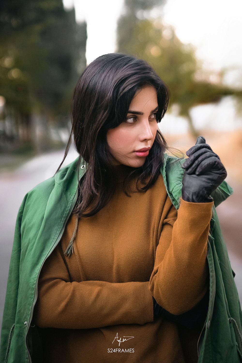 a woman wearing a green jacket and black gloves