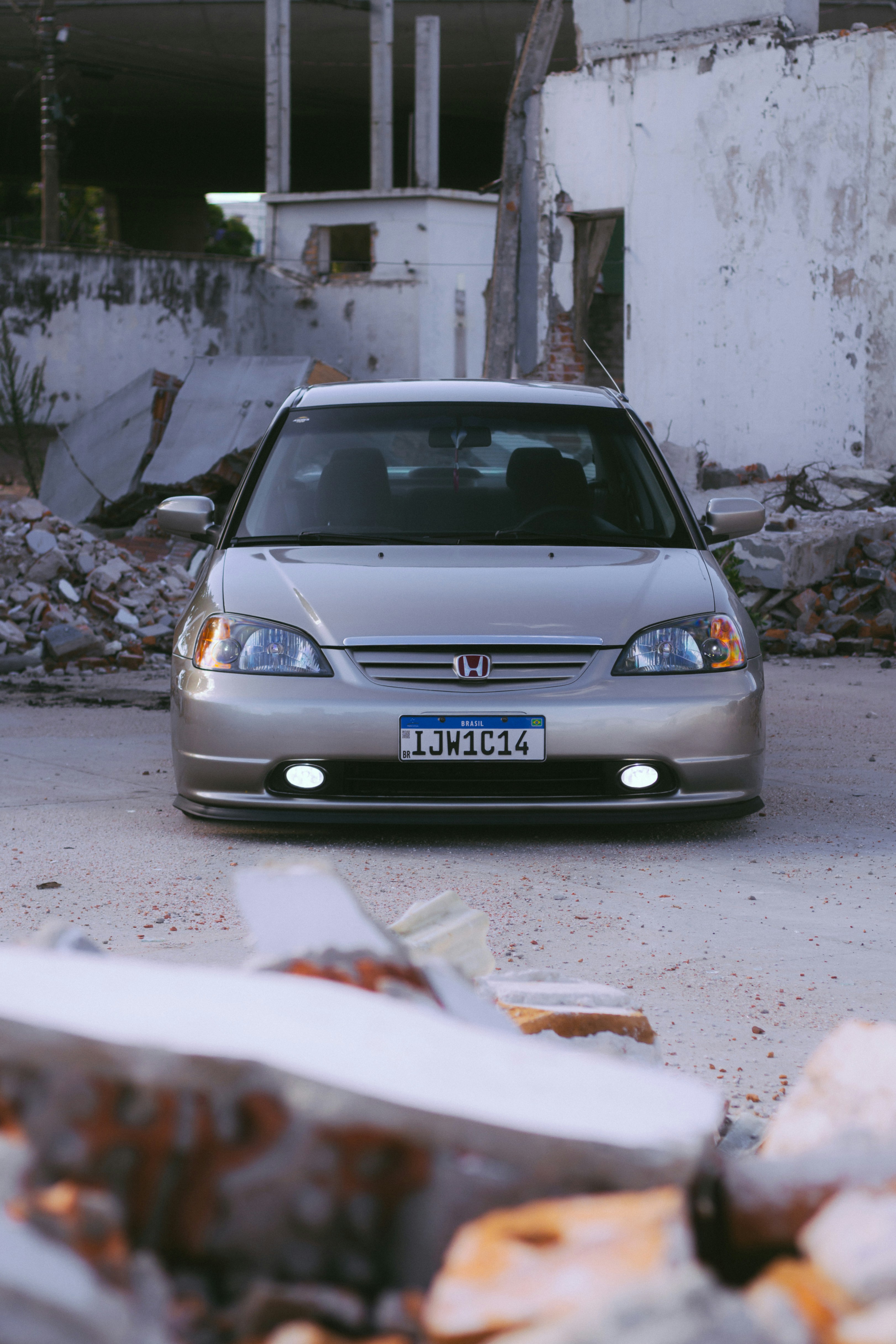 a silver car parked in front of a pile of junk