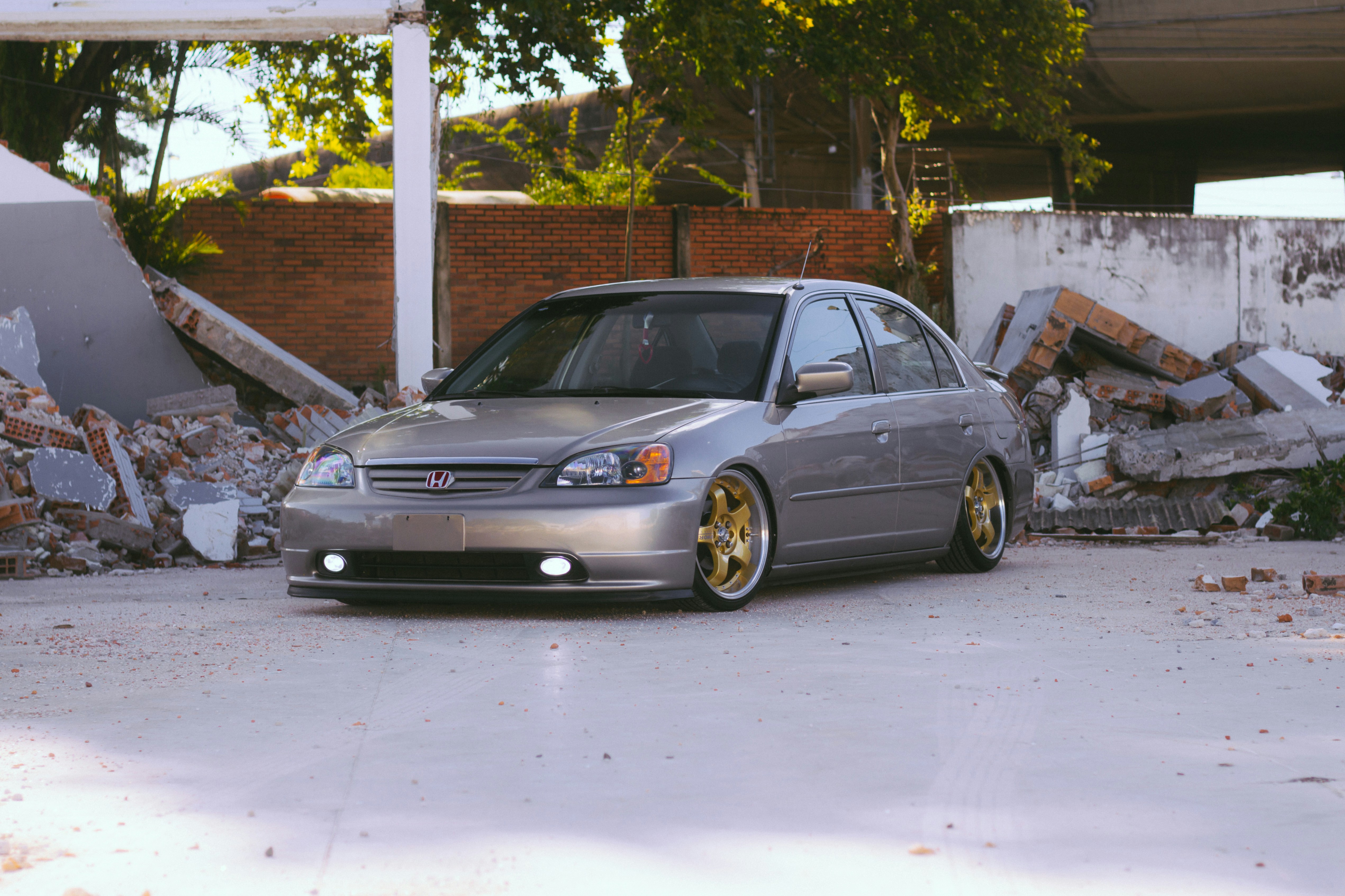 a silver car parked in front of a pile of rubble