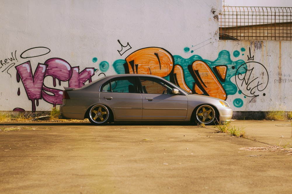 a car parked in front of a graffiti covered wall