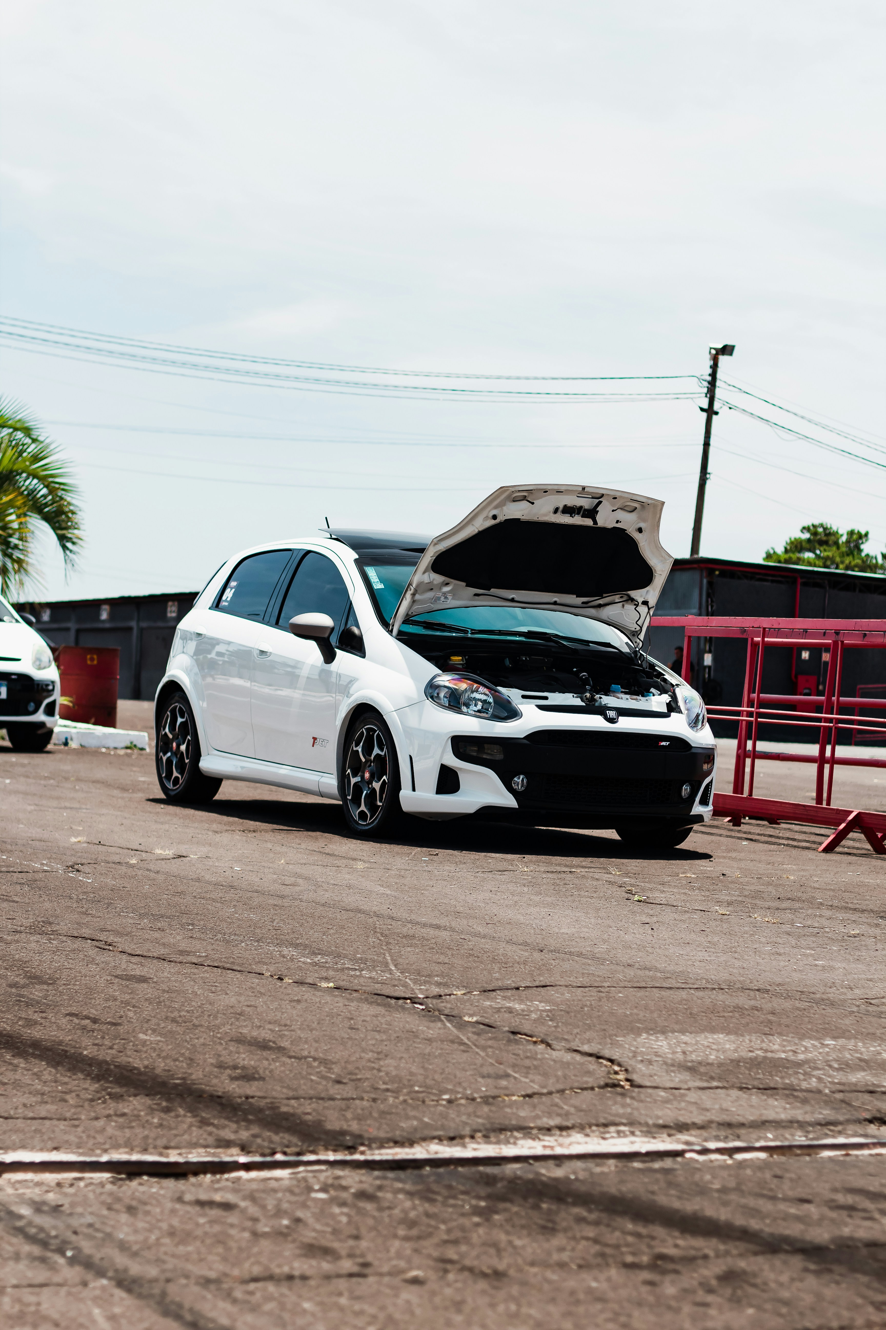 a white car with a broken hood parked in a parking lot