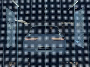 A sleek holographic display glowing with neon accents in a dark room, showcasing a futuristic car model.