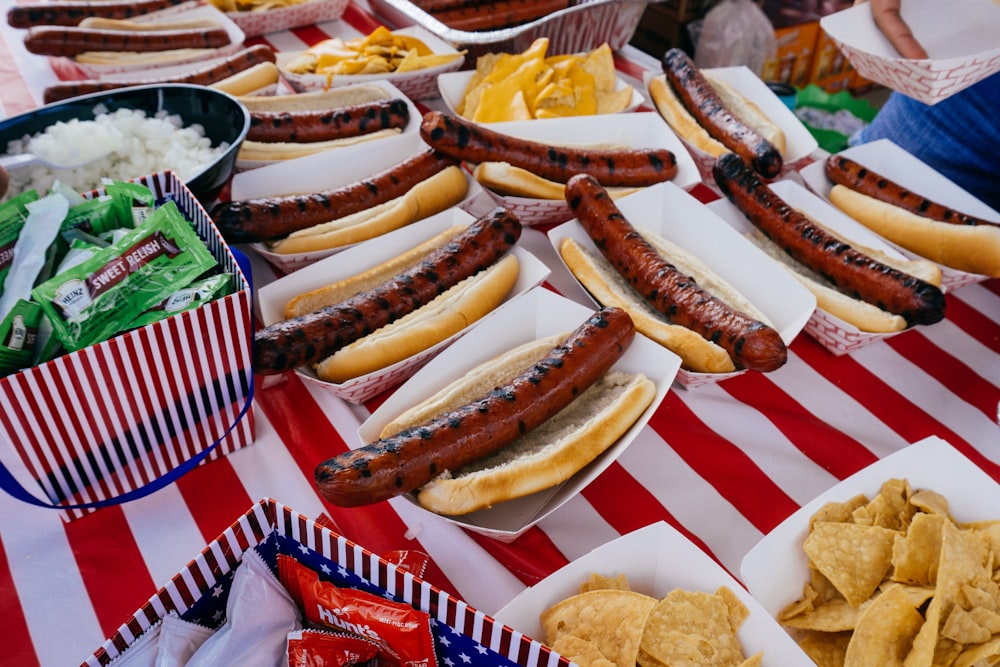 a table topped with lots of hot dogs and chips