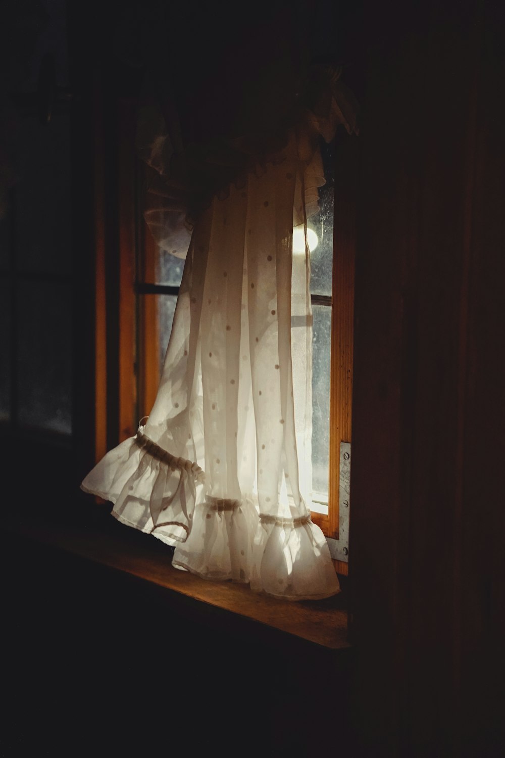 a window with a white curtain and a window sill