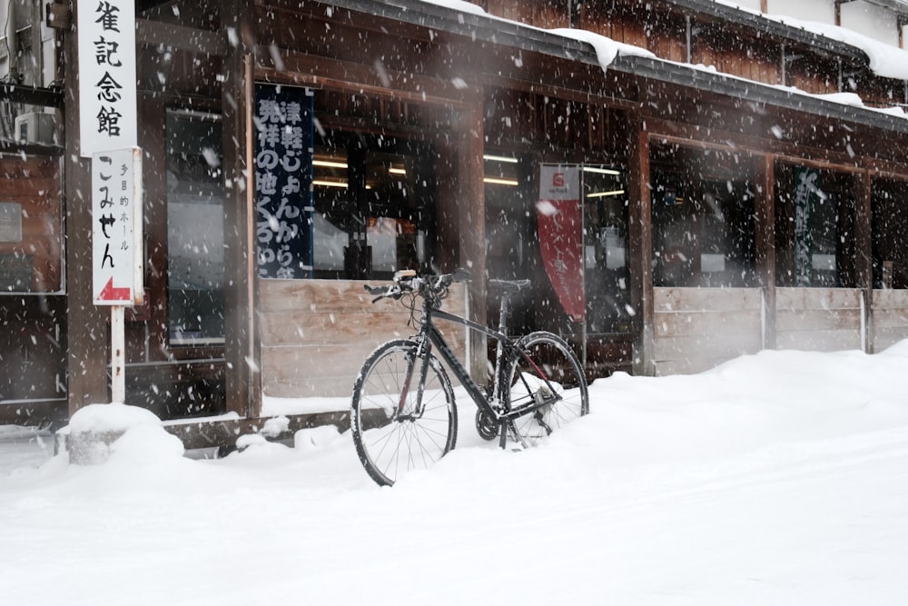 a bicycle parked in front of a building covered in snow