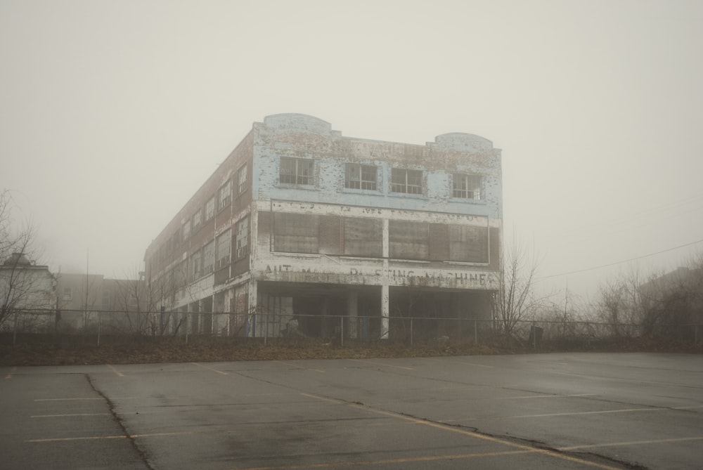 an abandoned building in a parking lot on a foggy day