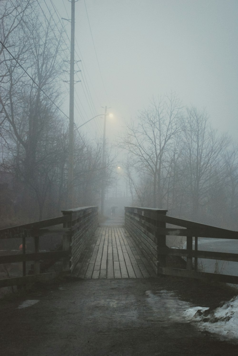 a foggy bridge with a street light in the distance