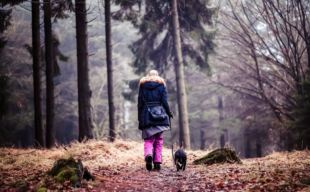 a woman walking her dog in the woods