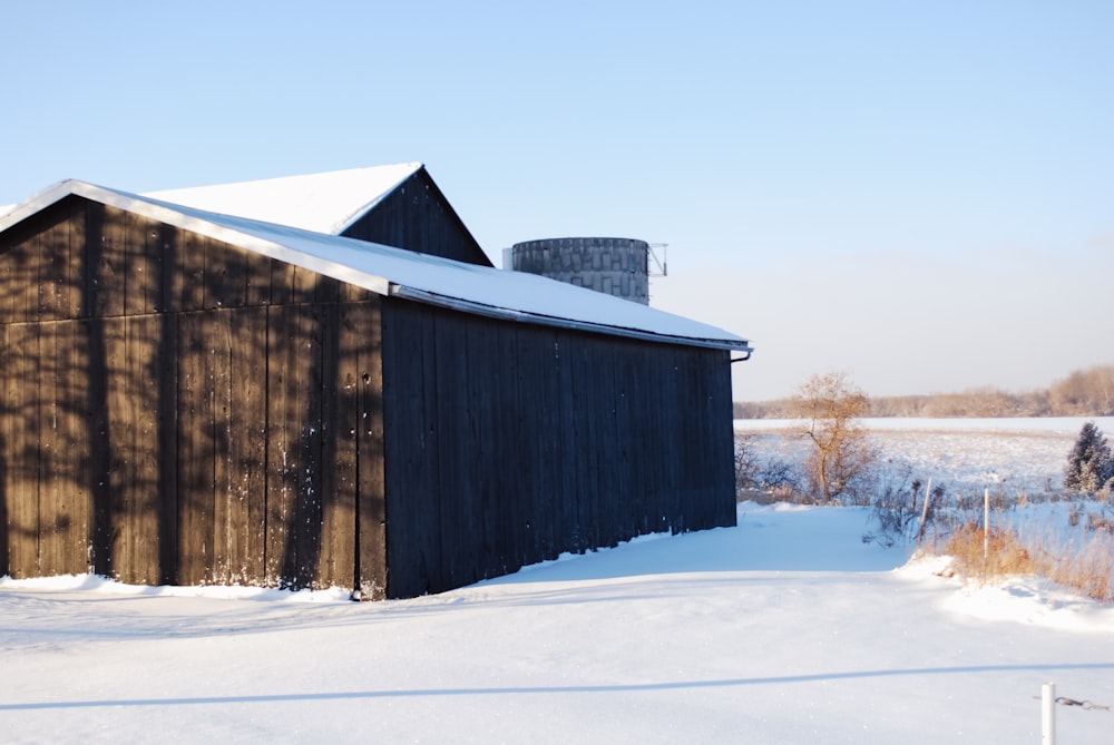 a barn in the middle of a snowy field