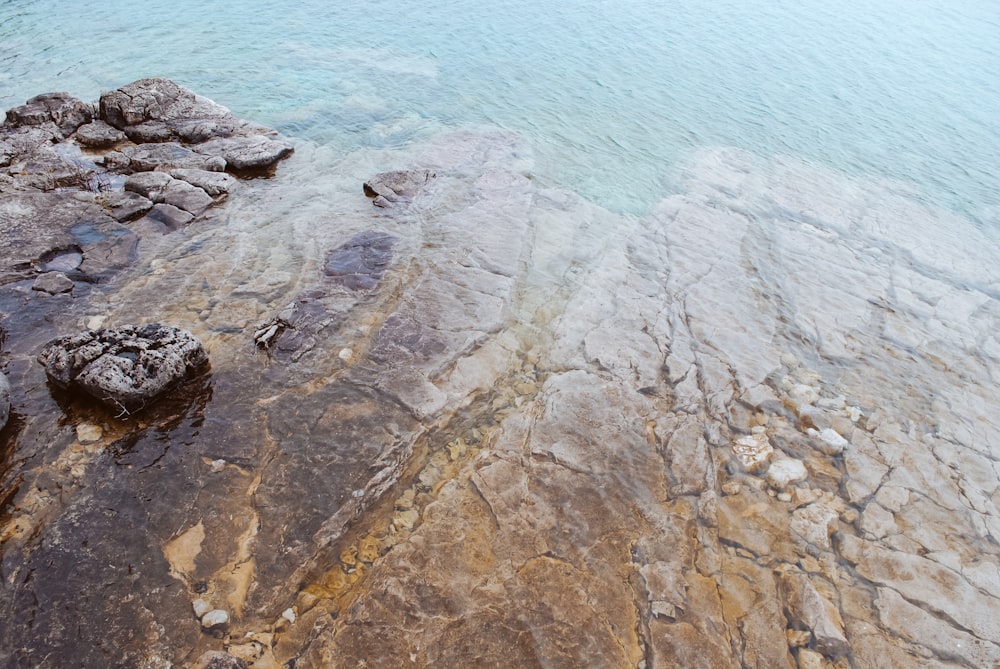 un gran cuerpo de agua sentado junto a una orilla rocosa