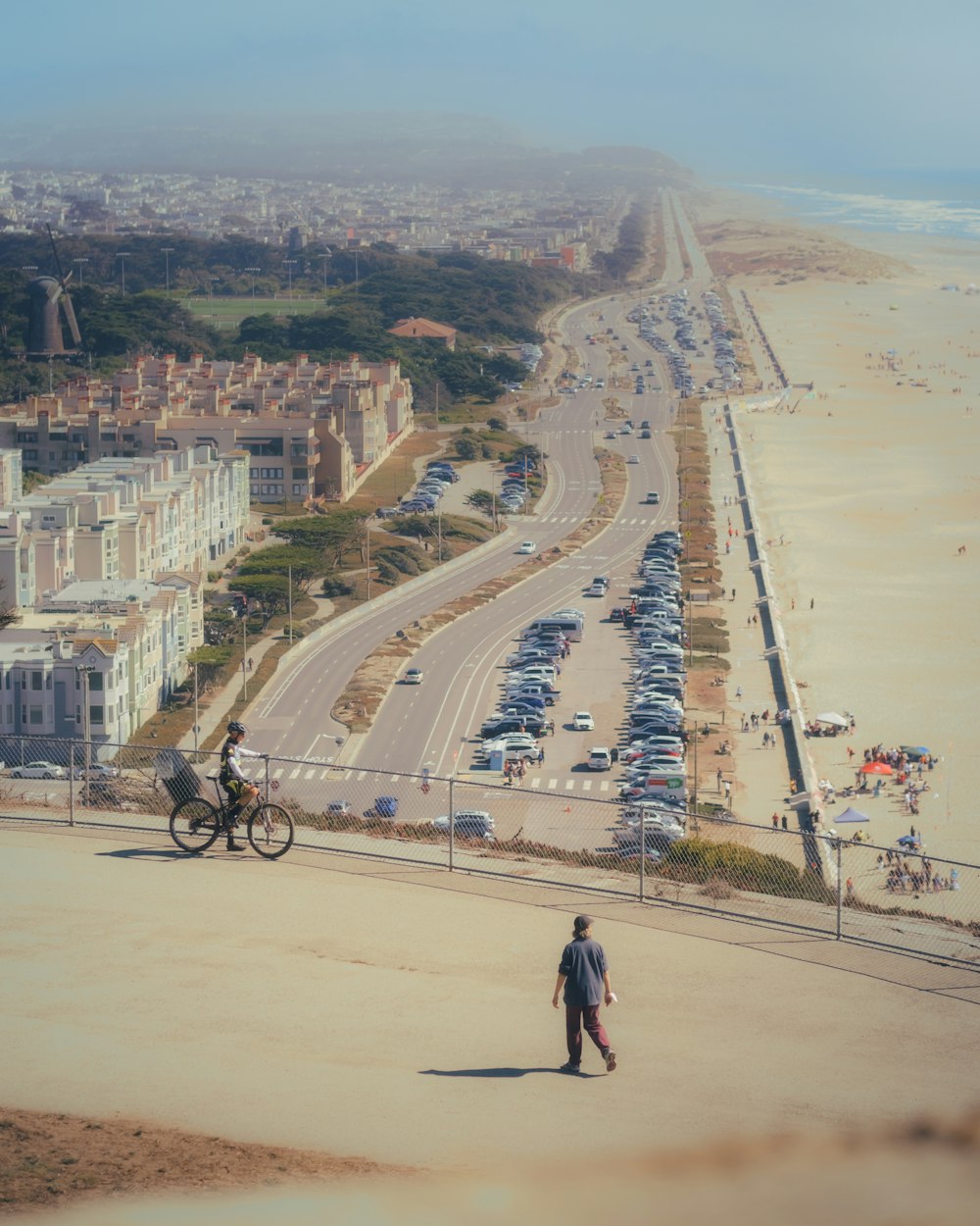 a man walking down a street next to a beach