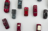 Collection of miniature cars arranged by color on a white surface