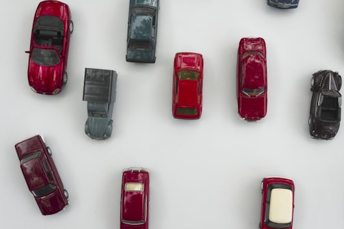 Collection of miniature cars arranged by color on a white surface