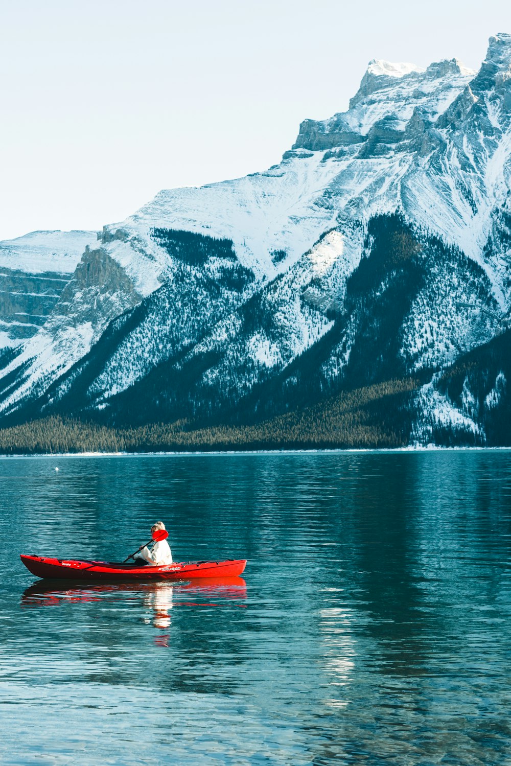 a man in a red canoe on a mountain lake
